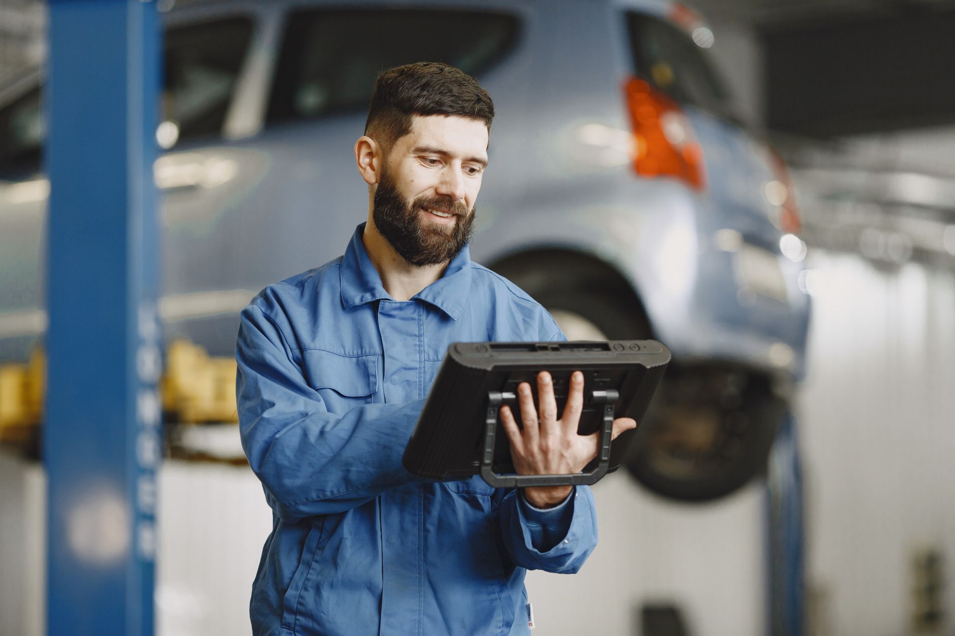 ein Sachverständiger in Arbeitskleidung fotografiert mit einer Digitalkamera den Frontschaden eines Kombis in einer Berl